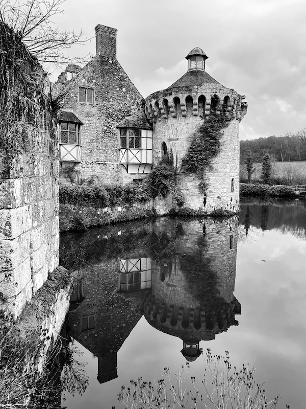 A castle in black and white. It is reflected in water