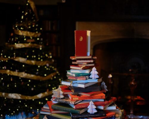 A Christmas tree made of books with a real tree behind