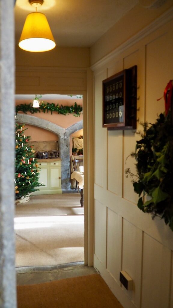 A corridor leading down to a kitchen with a Christmas tree