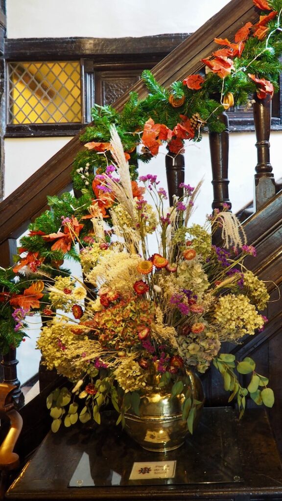 Dried flowers on a table in front of a bannister with a garland