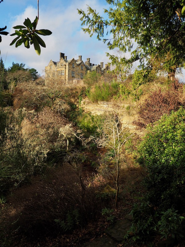 A view of a castle with a planted quarry garden in the foreground
