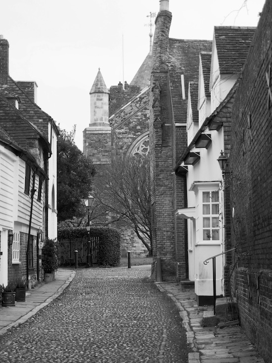 A black and white photo of a cobbled street with a church at one end